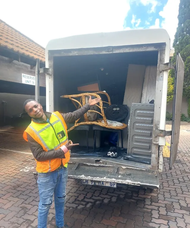 A Lewin Projects mover carefully carrying a wooden chair into the back of a removal truck