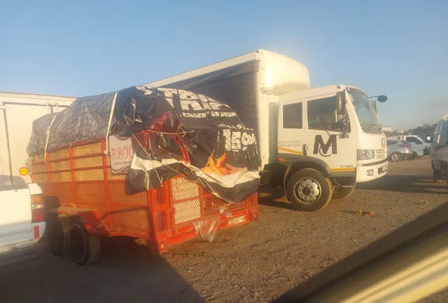 A Lewin Projects truck towing a covered and strapped trailer load on a nationwide transport run