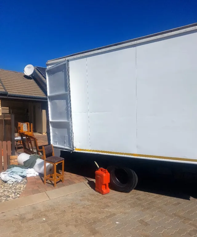 A large Lewin Projects removal truck alongside furniture waiting to be loaded at a residential property