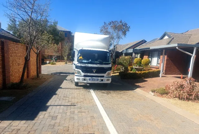 A Lewin Projects removal truck positioned in a paved residential driveway ahead of a house move